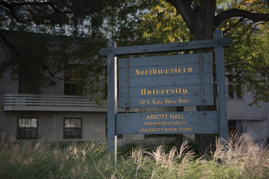 A weathered black wooden sign that reads, "Northwestern University – Abbott Hall