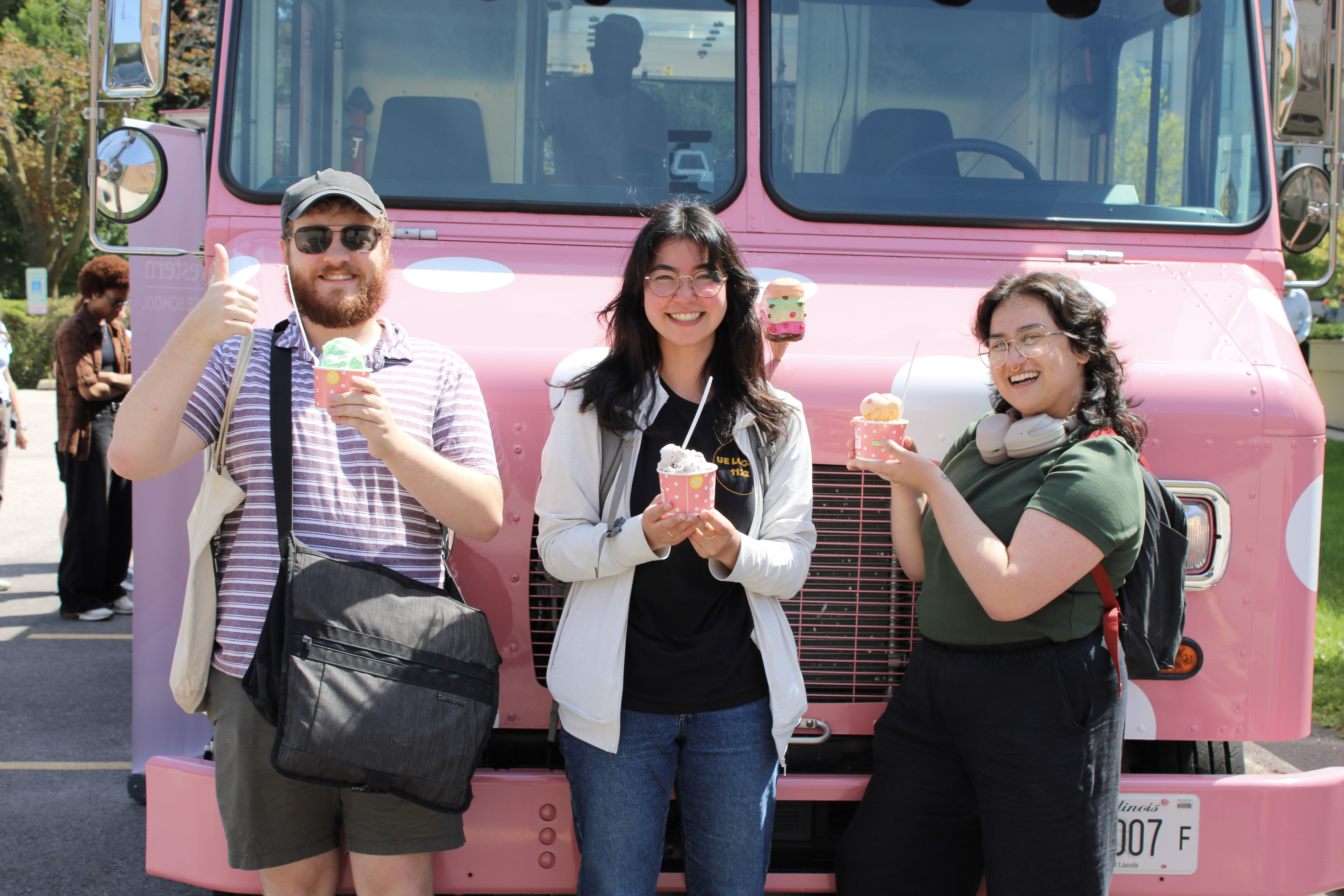 a group of students holding ice cream in front of a pink ice cream truck